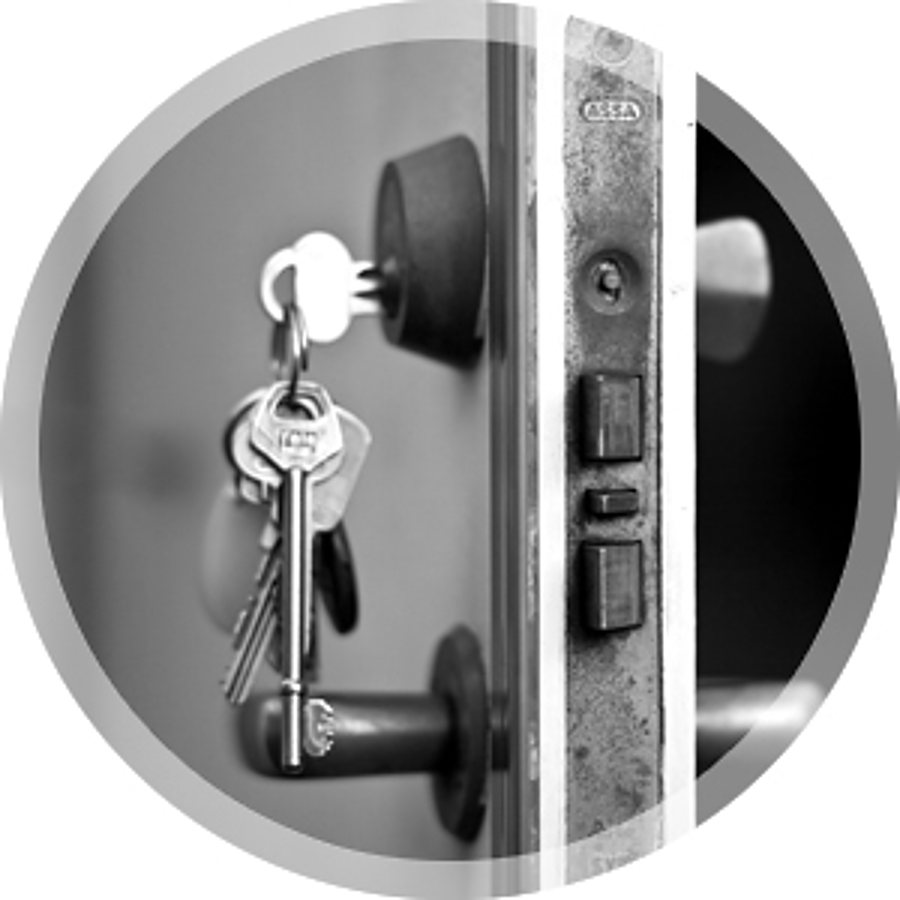 Photo en noir et blanc d’une porte entrouverte avec un trousseau de clés accroché dans le cylindre.